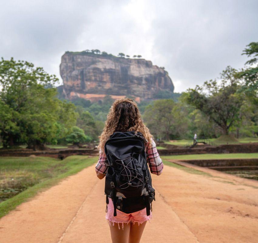Traveller with a backpack walking towards Sigiriya Rock Fortress, Sri Lanka